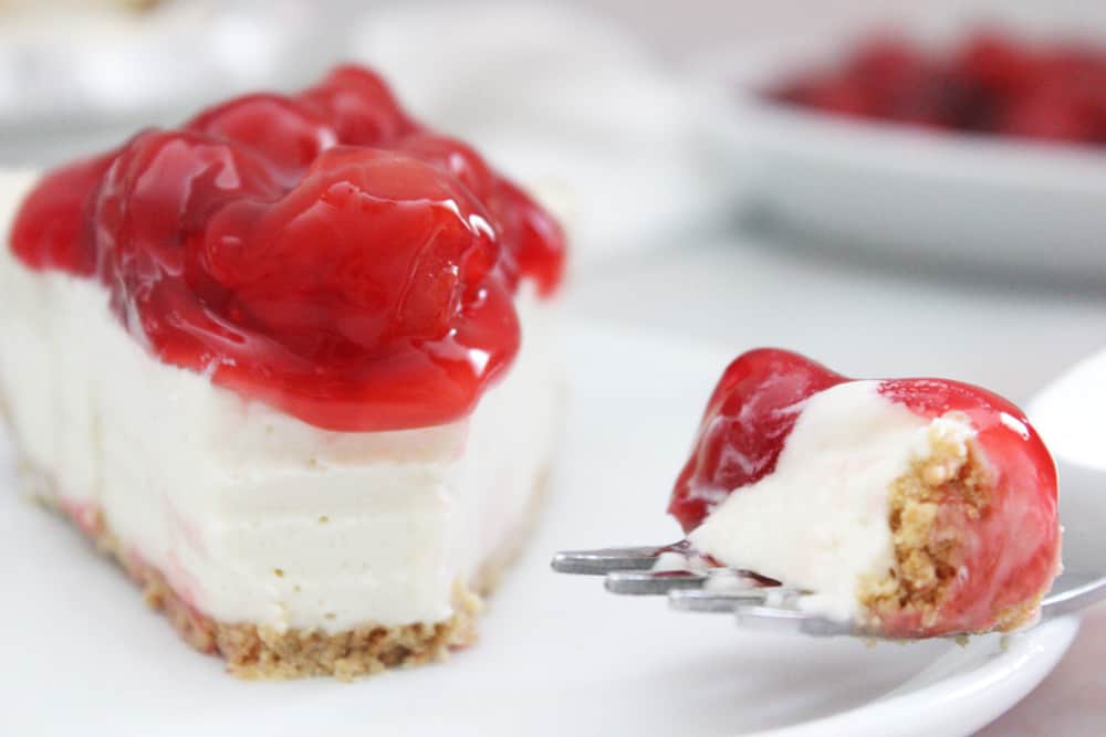 cream cheese pie on a white plate with a bite on a fork next to it also on the plate