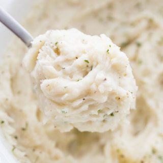 Slow Cooker Mashed Potatoes close up on a spoon with salt and pepper.