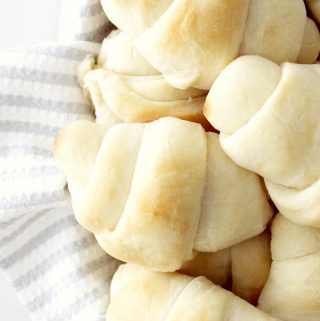 homemade rolls in a basket lined with a grey and white striped tea towel
