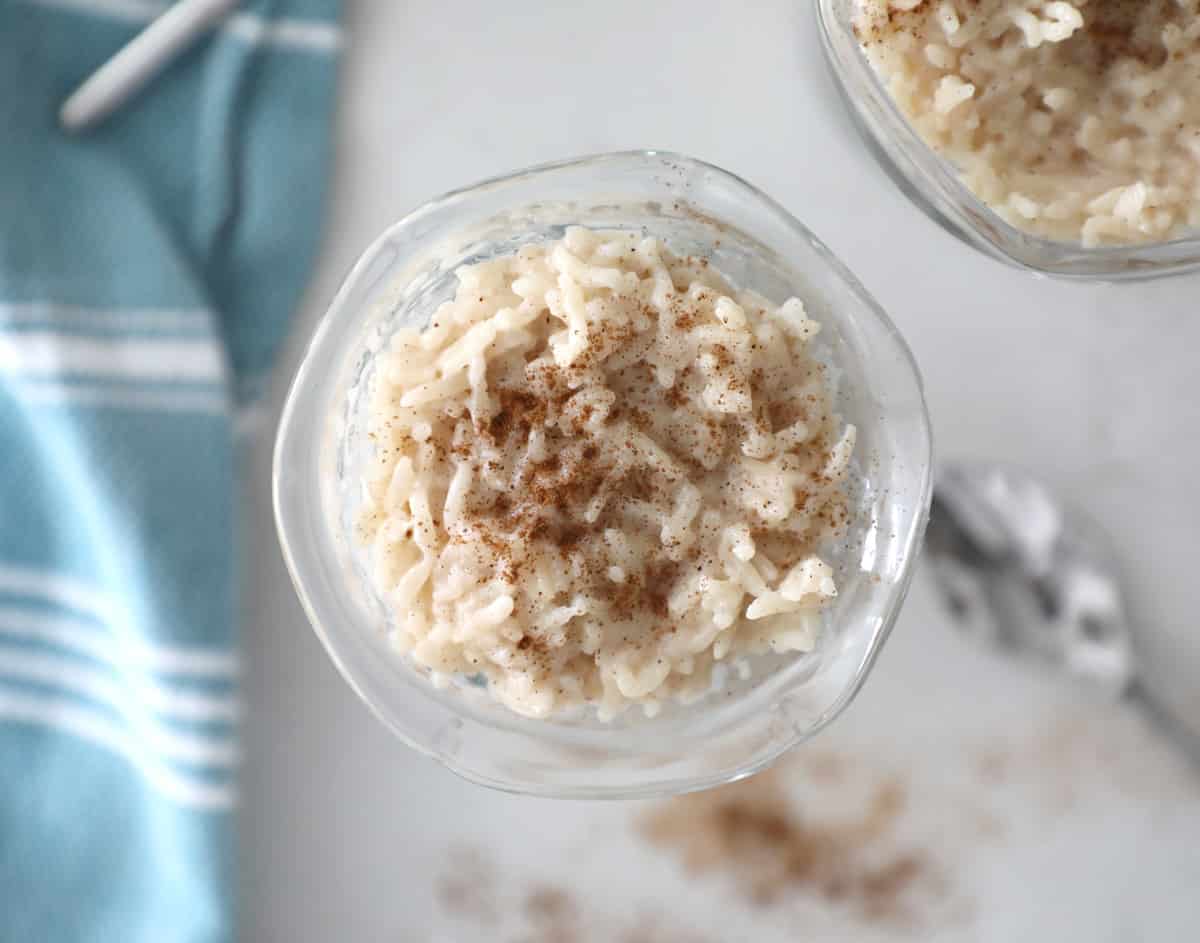 rice pudding on a white counter by some cinnamon and a blue tea towel
