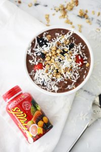 fruit capsules on a white tea towel next to a smoothie bowl and a spoon