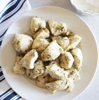 baked and seasoned chicken on a small white plate birds eye view
