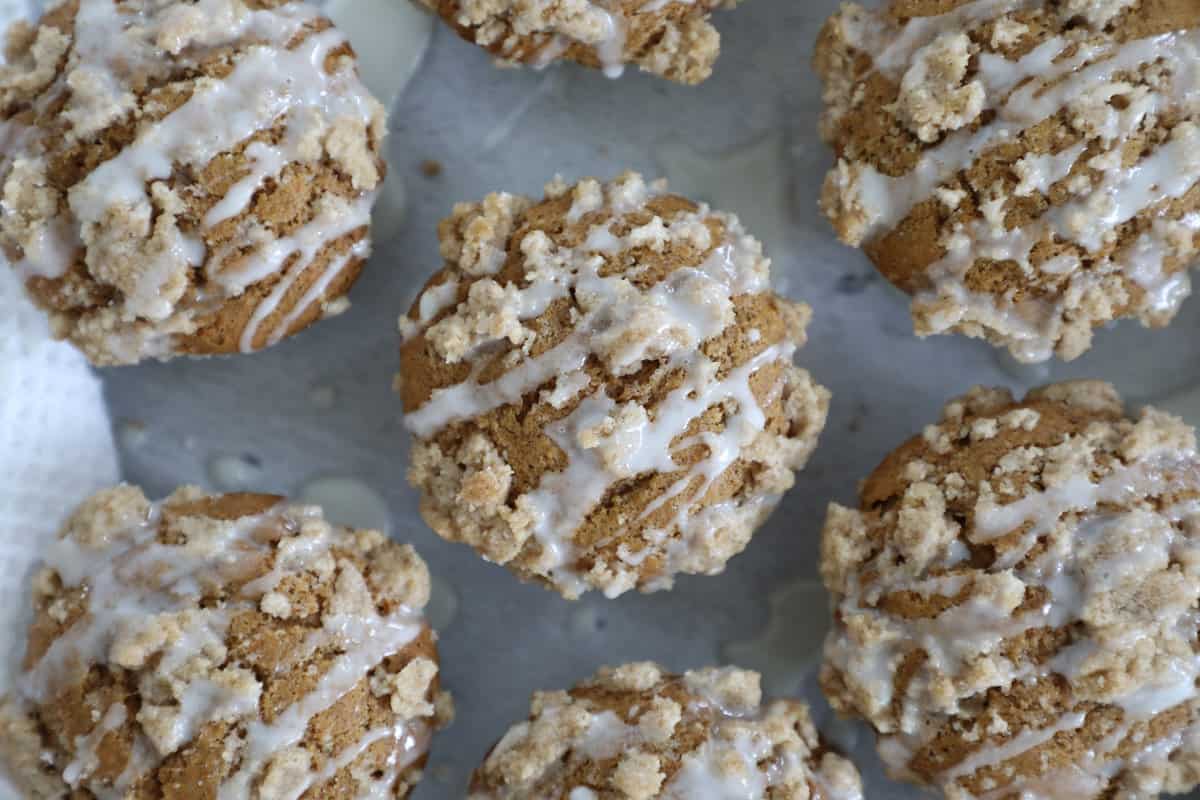 Bird's eye view of many pumpkin streusel muffins with vanilla glaze on top. 